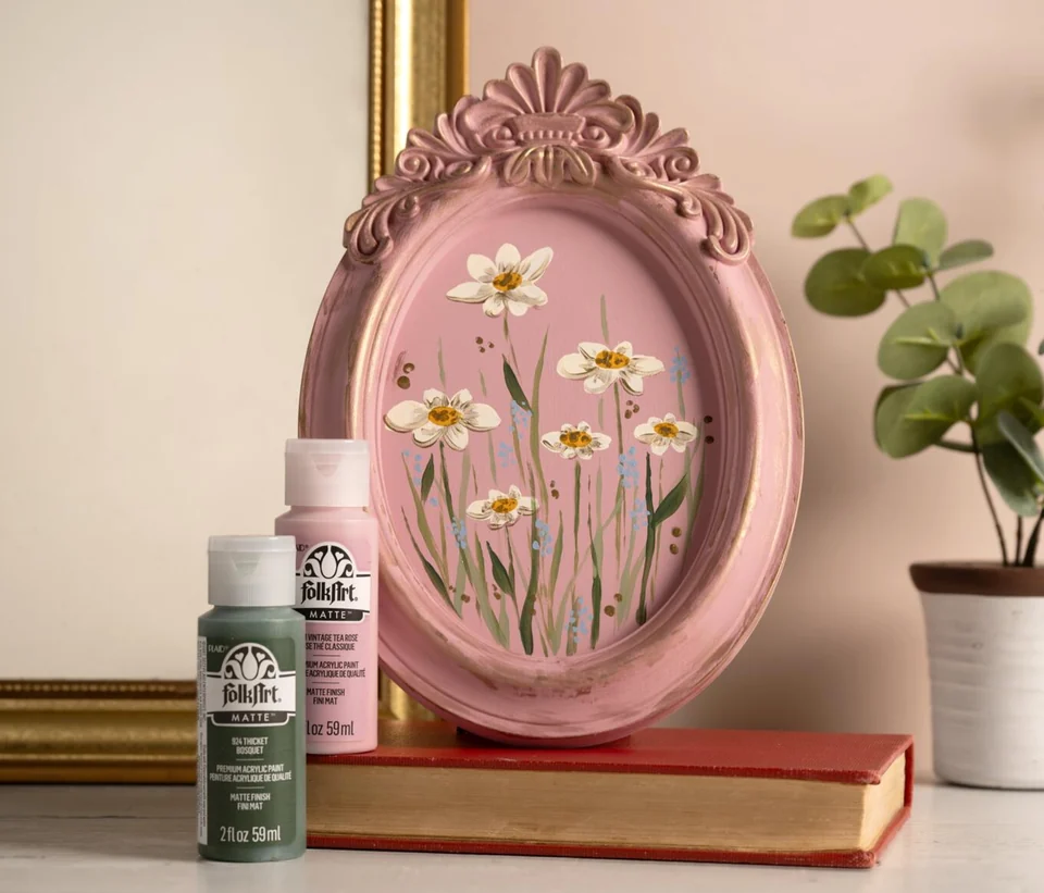 A painted pink decorative frame with flowers and FolkArt paints
